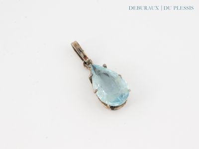 un gros plan d'un pendentif en topaze bleue posé sur une surface blanche
