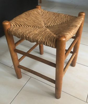 a wooden chair with a woven seat on a tile floor