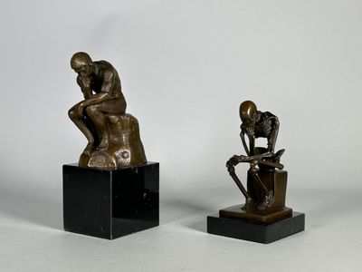 deux sculptures en bronze représentant un homme et une femme assis sur des cubes