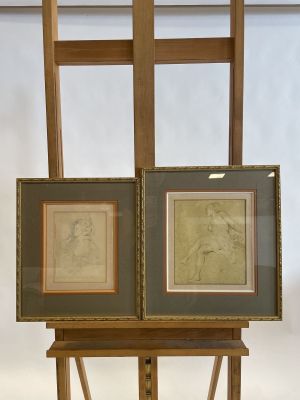 two framed drawings of a man and a woman on an easel