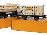 deux petits trains posés sur des cartons, sur une surface blanche