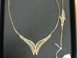 un collier en or orné d'une flèche, présenté dans un coffret noir