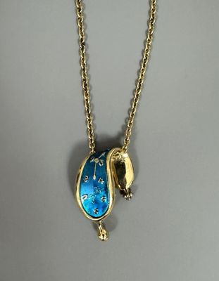 a close up of a gold necklace with a blue pendant on it