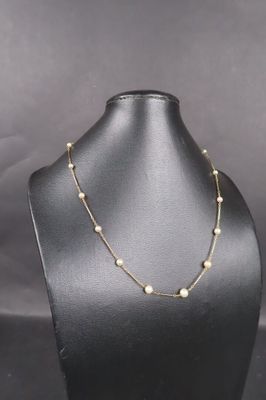 un mannequin noir portant un collier de perles dorées