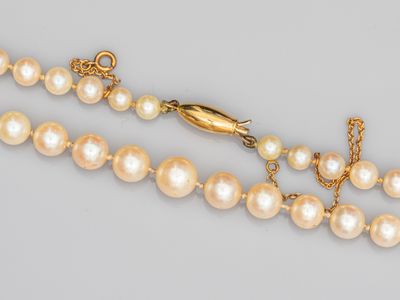 un gros plan sur un collier de perles muni d'un fermoir en or