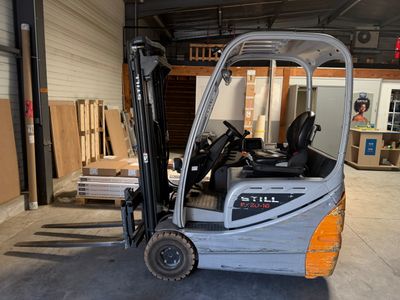 un chariot élévateur garé dans un entrepôt, avec des palettes en arrière-plan
