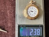 une montre de poche posée sur une balance, à côté d'un trousseau de clés