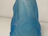 a blue glass vase sitting on a table next to a white wall