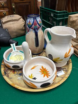 une table verte sur laquelle se trouvent des assiettes, des tasses et un vase