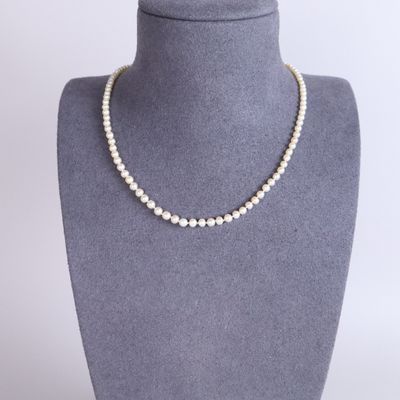 a white pearl necklace on a mannequin neck with a gold clasp