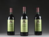 three bottles of red wine sitting on top of a table