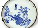 blue and white porcelain plate with a painting of a man and a woman in a landscape