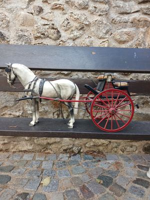 un cheval blanc tirant une calèche rouge sur un banc