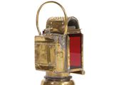 an antique brass lantern with a red glass inside on a white surface