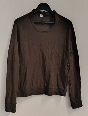 a brown sweater hanging on a hanger against a white wall