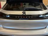 the rear end of a silver car with the hood open
