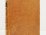 un vieux livre à la couverture marron, rehaussée de dorures sur fond blanc
