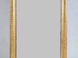 un miroir à cadre doré posé sur une table blanche