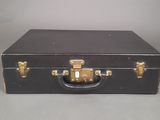 a black suitcase with gold handles on a gray surface