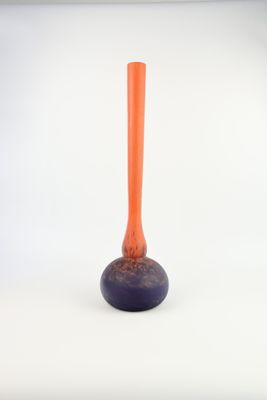 un petit vase orange posé sur une table blanche