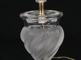 une lampe en verre transparent avec un pied doré sur fond noir