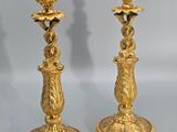 pair of antique brass candlesticks on a table with a shadow of a person