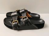 pair of black sandals with gold buckles on them on a white surface