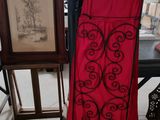 une robe rouge suspendue à un portant à côté d'un tableau
