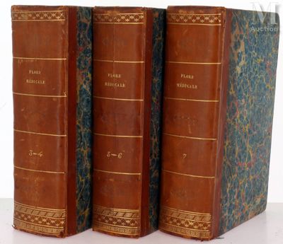 trois vieux livres posés l'un sur l'autre sur une surface blanche