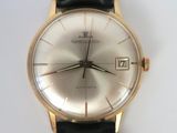 a gold wrist watch with a black leather strap