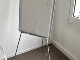 a white board in the corner of a room next to a chair