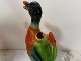 un oiseau en céramique au bec vert et orange