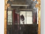 une image représentant un miroir à cadre doré accroché au mur d'une pièce