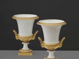 deux vases blancs et dorés munis d'anses, posés sur une table