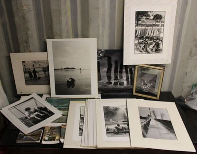 Plusieurs photographies en noir et blanc sont posées sur une table près d'un mur.