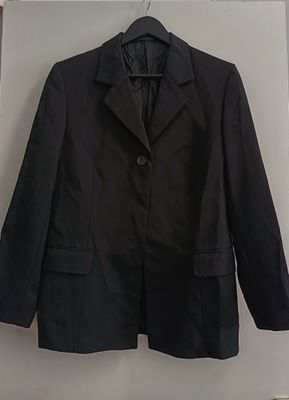 black blazer jacket hanging on a wall in a white room