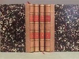two old books sitting on top of a table next to each other