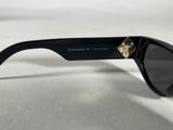 black sunglasses with gold details on the sides of them on a white surface