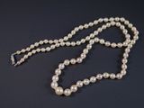 gros plan d'un collier de perles blanches sur une surface noire