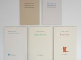 four books on a white table with a red chair in front of them