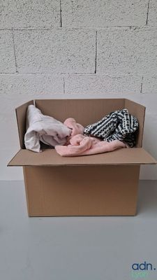 une boîte en carton contenant des vêtements, posée sur une table