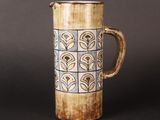 a brown and blue vase with a handle on a table