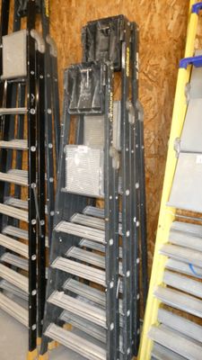 Plusieurs échelles sont alignées contre un mur dans un débarras.