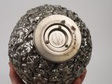 someone is holding a silver object in their hand on a gray background