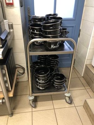 many pots and pans stacked on a cart in the kitchen