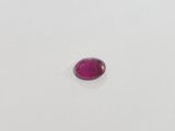 a pink oval shaped ruby stone on a white surface