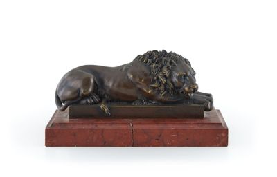 une statue en bronze représentant un lion, posée sur un socle en marbre rouge