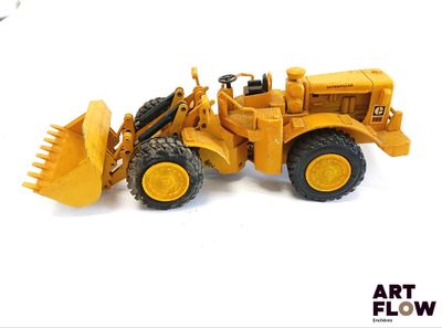 un petit bulldozer jaune posé sur une surface blanche