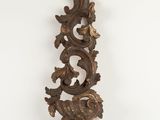 an ornately carved wooden wall hanging on a white wall