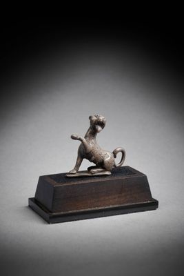 une figurine en bronze représentant un chien, posée sur un socle en bois